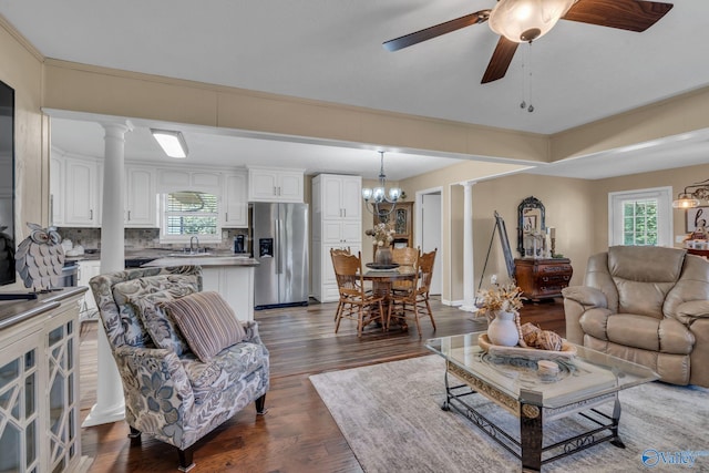 living room with ceiling fan with notable chandelier, dark hardwood / wood-style flooring, ornate columns, and sink