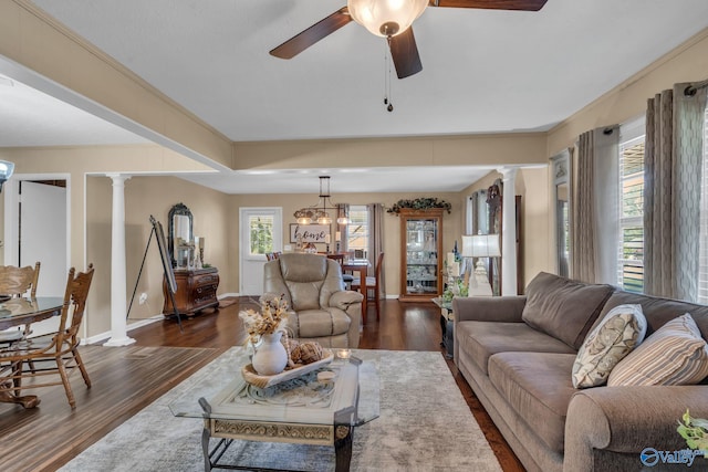 living room with decorative columns, dark hardwood / wood-style flooring, plenty of natural light, and ceiling fan with notable chandelier