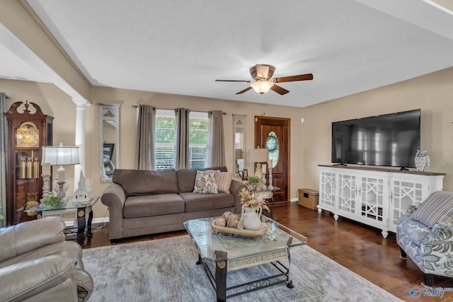 living room with ceiling fan, dark hardwood / wood-style flooring, and ornate columns