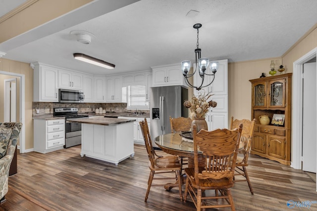 kitchen with dark hardwood / wood-style flooring, pendant lighting, white cabinets, and stainless steel appliances