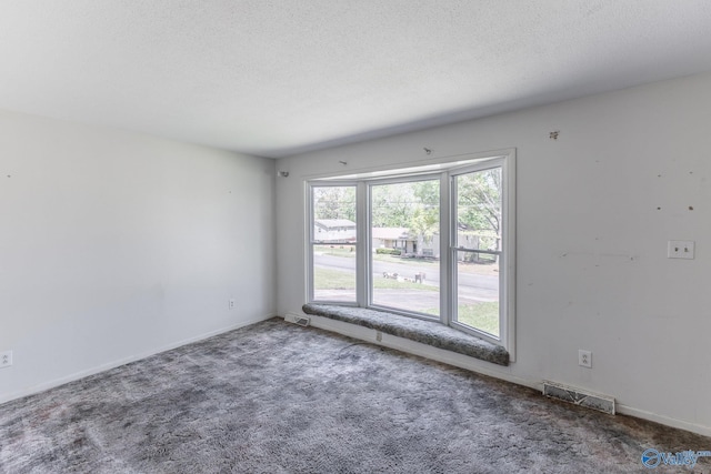 carpeted spare room with baseboards, visible vents, and a textured ceiling