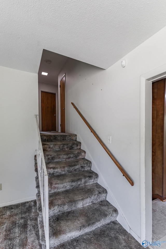 staircase featuring baseboards and a textured ceiling
