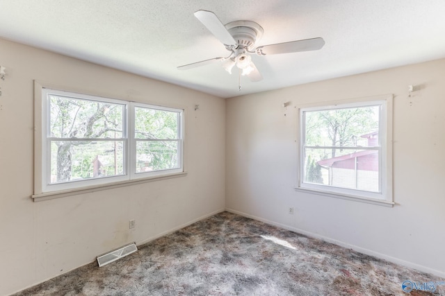 spare room featuring plenty of natural light, visible vents, a ceiling fan, and carpet floors