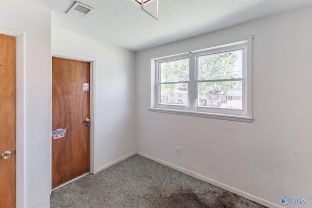 empty room with baseboards, visible vents, carpet, and a textured ceiling