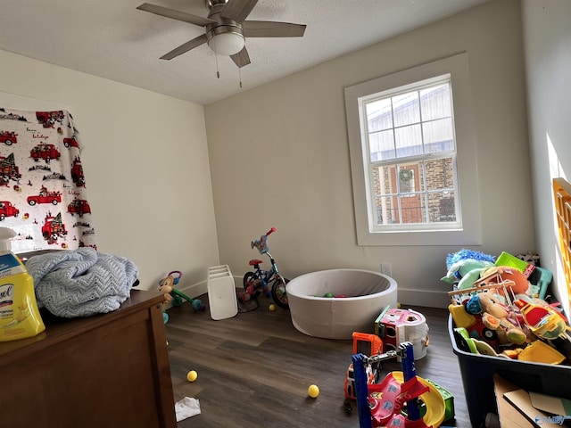 rec room featuring a textured ceiling, ceiling fan, wood finished floors, and baseboards