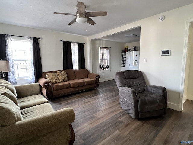 living area with dark wood-style floors, a ceiling fan, and baseboards