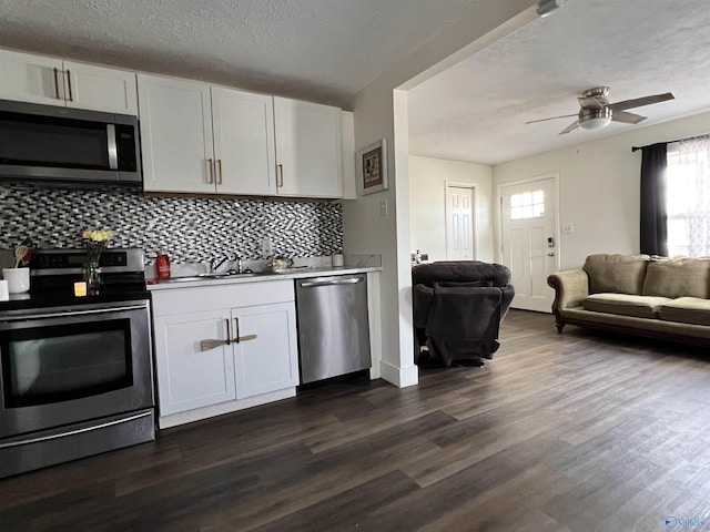 kitchen featuring tasteful backsplash, white cabinets, open floor plan, dark wood-type flooring, and stainless steel appliances