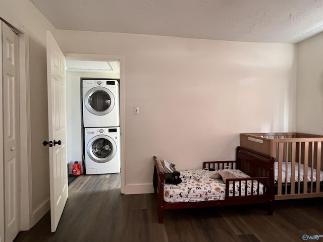 bedroom featuring stacked washer / drying machine, baseboards, and wood finished floors