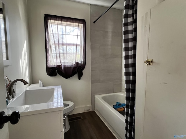 full bath with visible vents, toilet, shower / bath combo with shower curtain, vanity, and wood finished floors