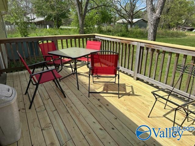 wooden deck featuring a lawn and outdoor dining space