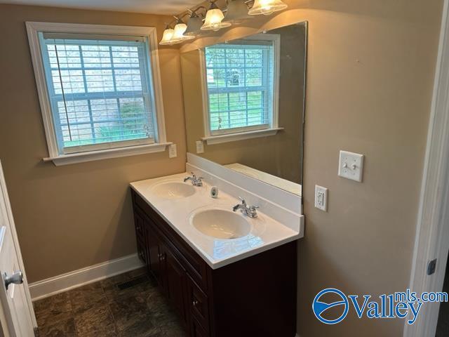 bathroom featuring double vanity, a sink, and baseboards