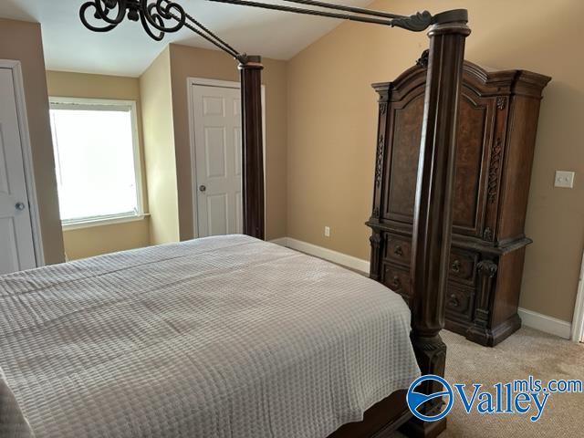 bedroom featuring an inviting chandelier, light carpet, and baseboards