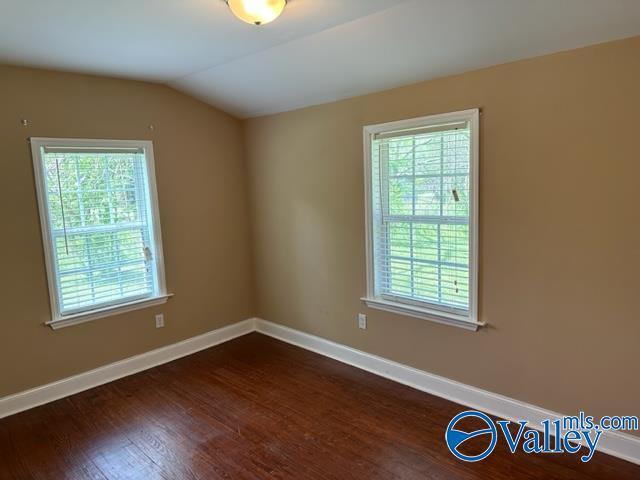unfurnished room with baseboards, lofted ceiling, and dark wood-type flooring