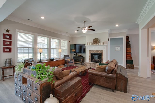 living room featuring ceiling fan, light hardwood / wood-style flooring, crown molding, and a fireplace