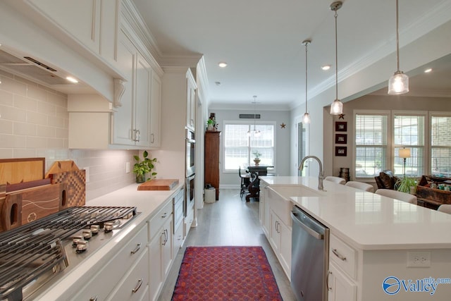 kitchen featuring sink, white cabinets, an island with sink, backsplash, and appliances with stainless steel finishes