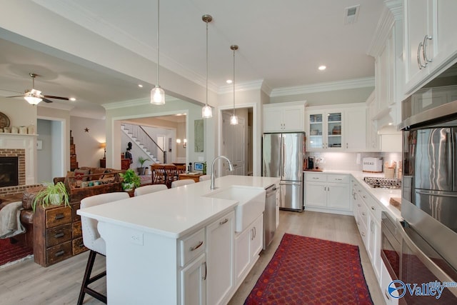 kitchen with sink, white cabinetry, an island with sink, a breakfast bar area, and appliances with stainless steel finishes