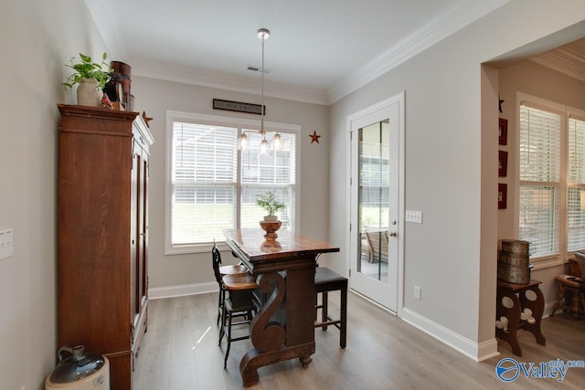 dining area with crown molding, a notable chandelier, and light hardwood / wood-style flooring