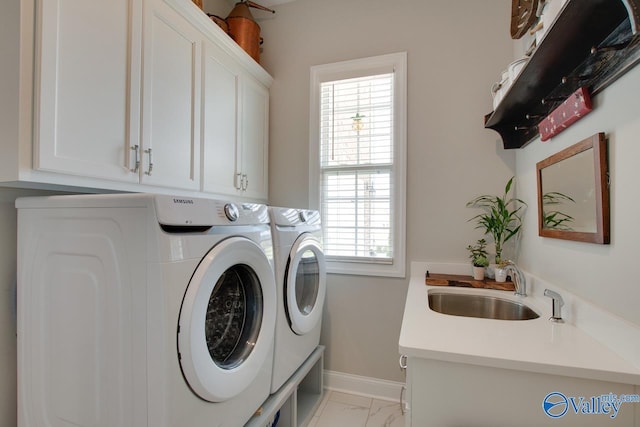 washroom with sink, washing machine and dryer, plenty of natural light, and cabinets