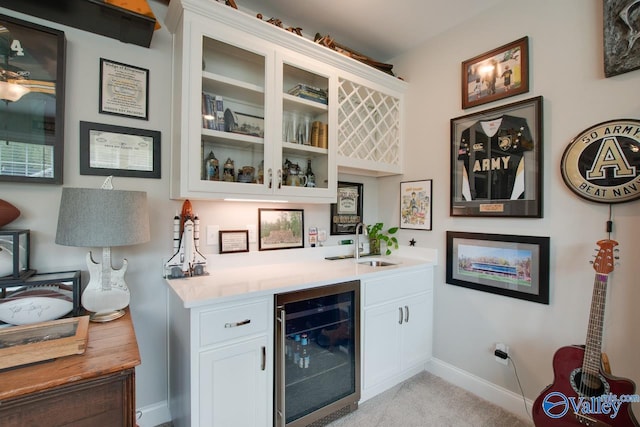 bar with sink, light colored carpet, wine cooler, and white cabinetry