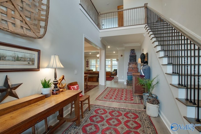 entryway with a towering ceiling, hardwood / wood-style flooring, and ornamental molding