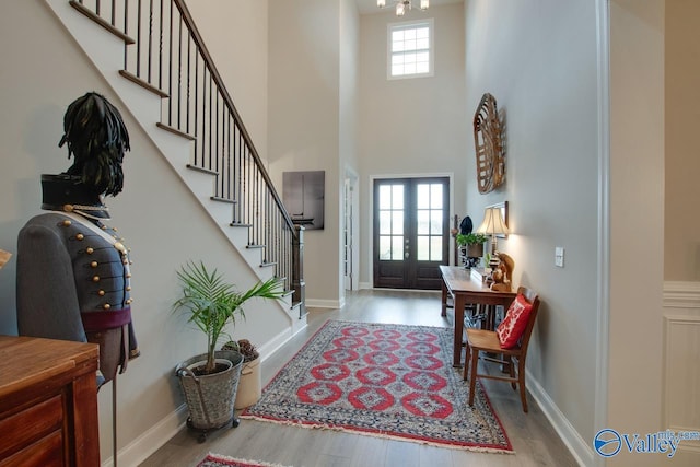 entrance foyer with french doors, a high ceiling, and light hardwood / wood-style floors