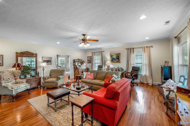 living area with baseboards, visible vents, ornamental molding, wood-type flooring, and a textured ceiling