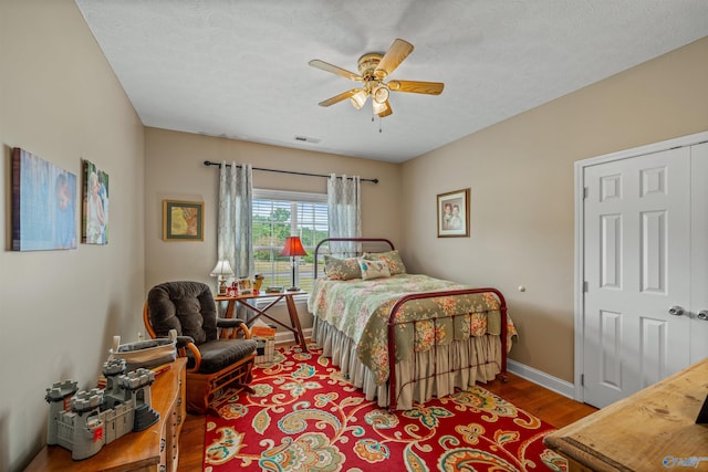 bedroom with visible vents, ceiling fan, baseboards, wood finished floors, and a textured ceiling