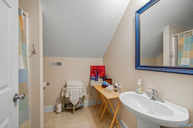 full bathroom with visible vents, lofted ceiling, a sink, a textured ceiling, and baseboards