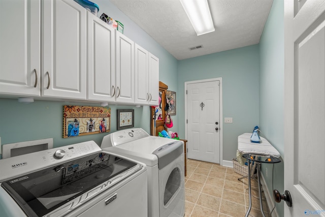 laundry area featuring visible vents, washer and clothes dryer, a textured ceiling, cabinet space, and light tile patterned floors