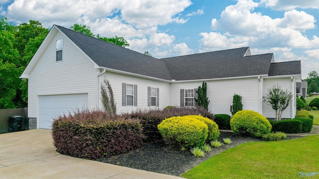 view of side of property featuring a lawn, a garage, driveway, and roof with shingles