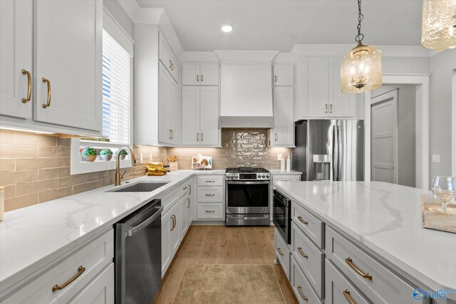 kitchen featuring decorative light fixtures, light wood-type flooring, appliances with stainless steel finishes, white cabinetry, and sink