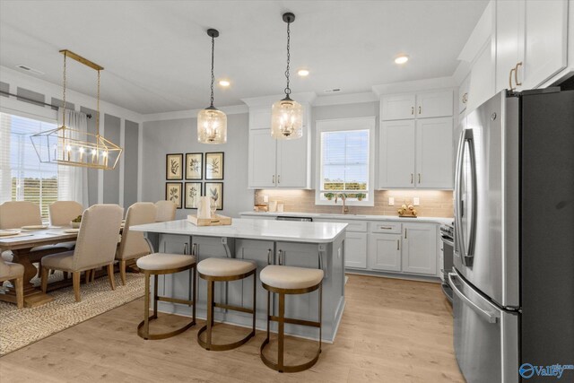 kitchen with white cabinetry, tasteful backsplash, a kitchen island, hanging light fixtures, and appliances with stainless steel finishes