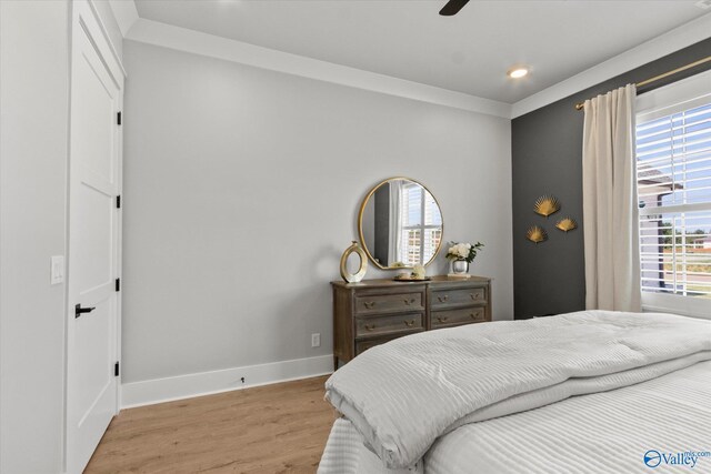 bedroom featuring multiple windows, wood-type flooring, ceiling fan, and ornamental molding