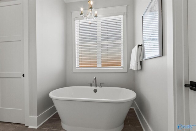 bathroom featuring a notable chandelier, tile patterned floors, and a washtub