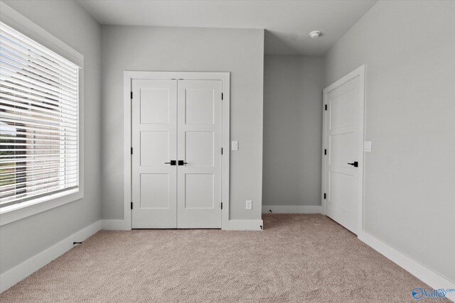 unfurnished bedroom featuring a closet and light carpet