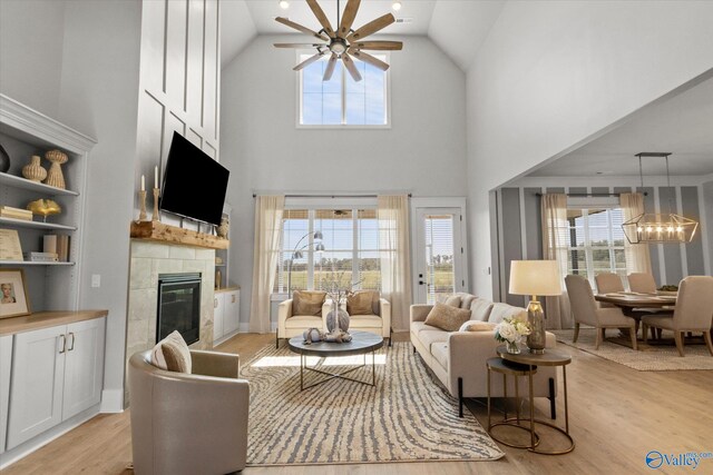 living room with ceiling fan with notable chandelier, light wood-type flooring, and high vaulted ceiling