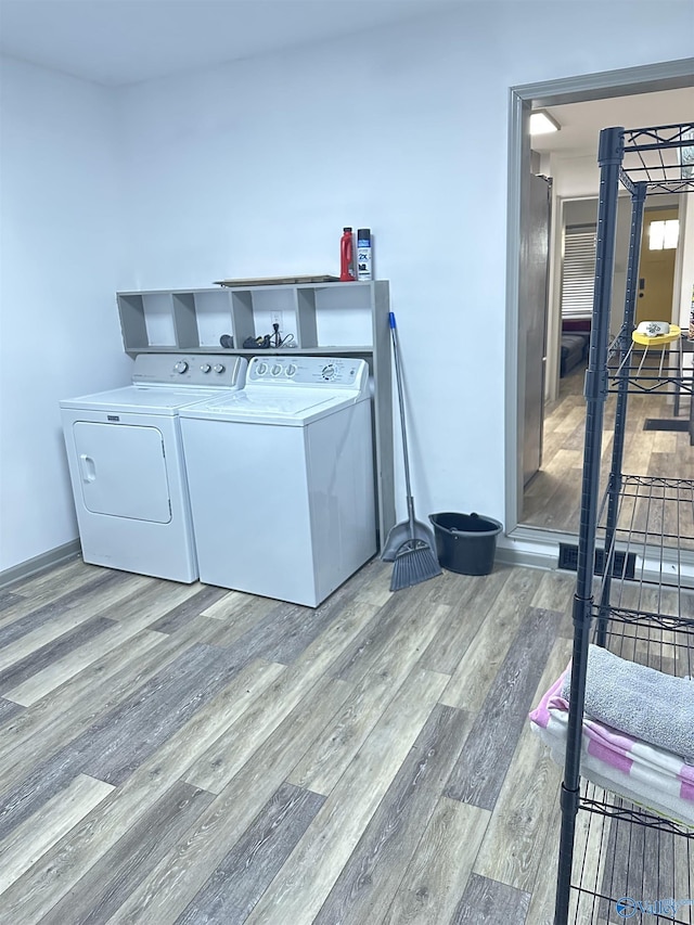 laundry room with washer and clothes dryer and light hardwood / wood-style flooring