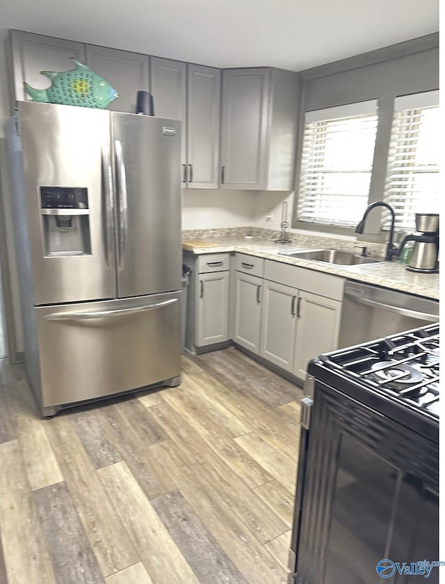 kitchen with stainless steel appliances, sink, light hardwood / wood-style floors, and gray cabinets