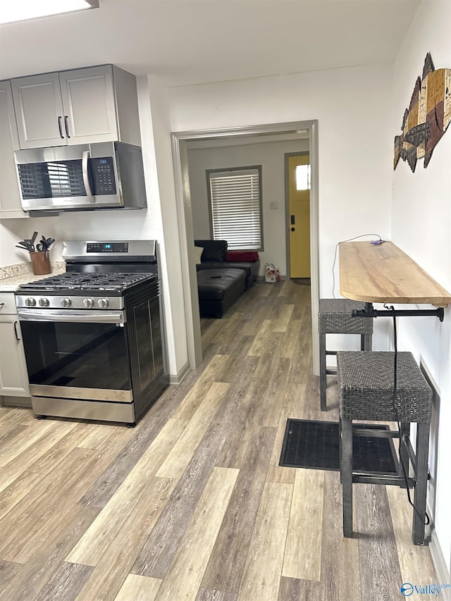 kitchen with stainless steel appliances, light wood-type flooring, and gray cabinetry