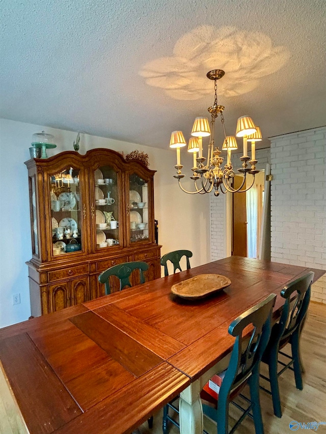 dining area with light wood-type flooring, brick wall, and a textured ceiling