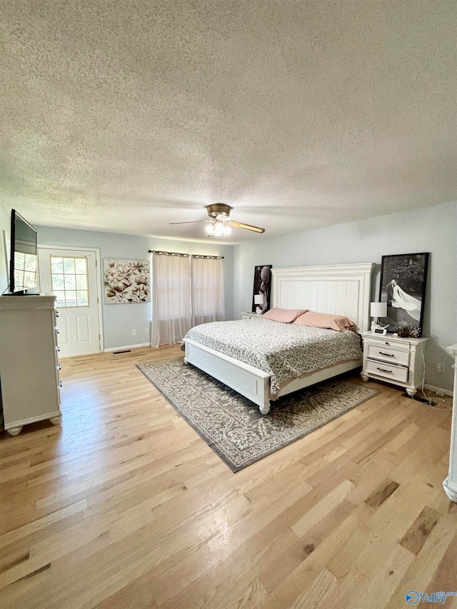 bedroom featuring light hardwood / wood-style flooring, a textured ceiling, and ceiling fan