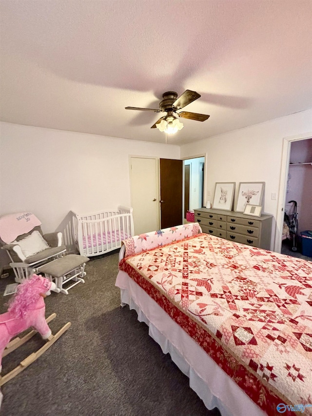 bedroom featuring ceiling fan, a textured ceiling, and dark colored carpet