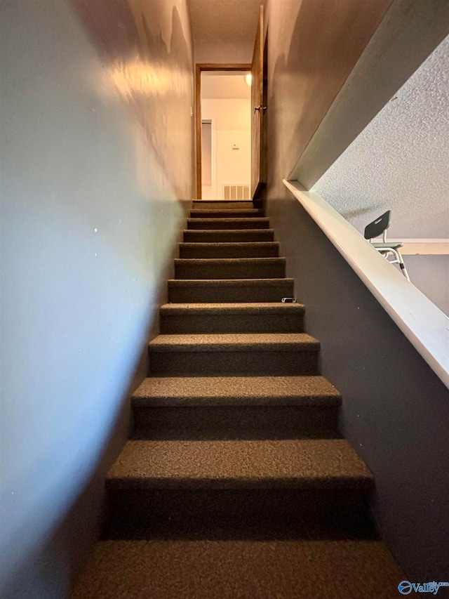 stairs featuring a textured ceiling