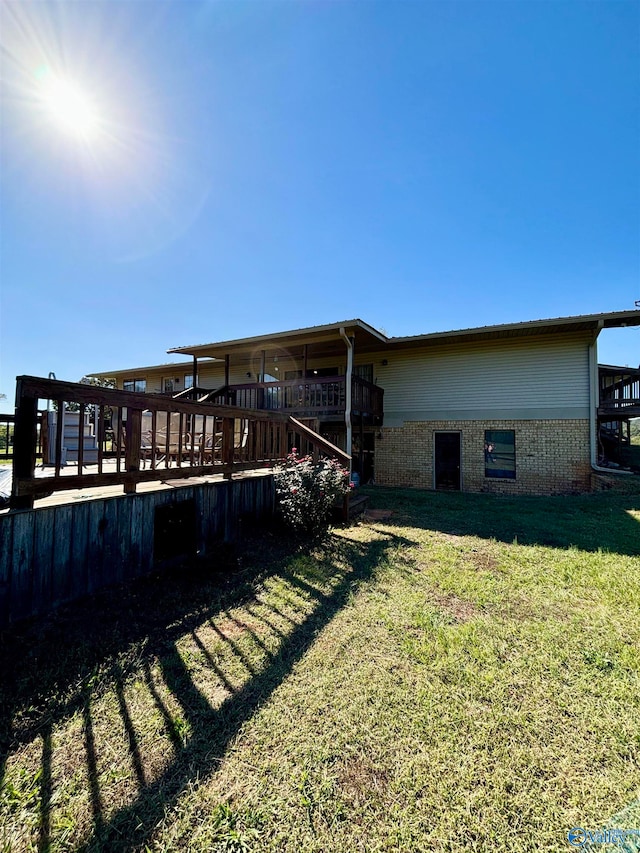 back of property featuring a wooden deck and a yard