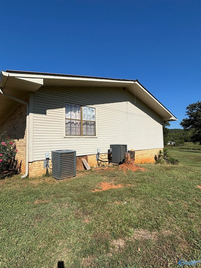 view of side of home with central air condition unit and a lawn