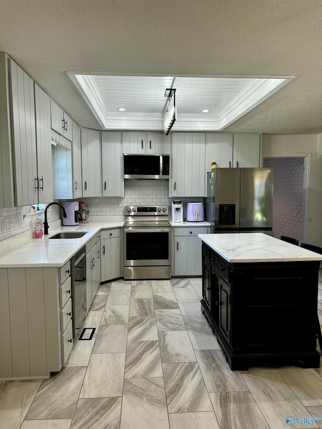 kitchen featuring decorative backsplash, a tray ceiling, appliances with stainless steel finishes, and sink