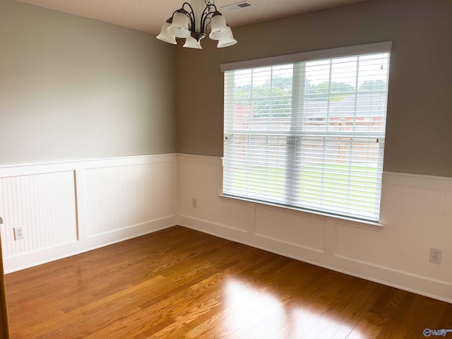 unfurnished room with hardwood / wood-style flooring and a chandelier