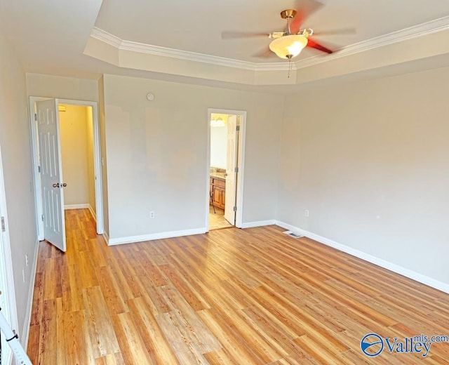 empty room featuring a tray ceiling, ornamental molding, ceiling fan, and light hardwood / wood-style floors