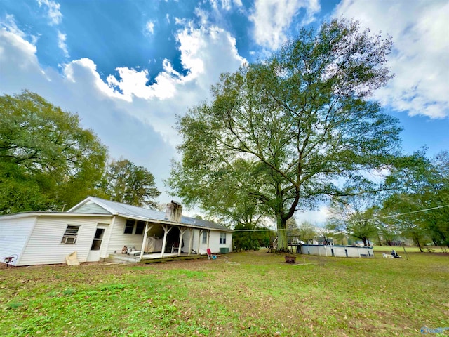 back of property featuring a chimney, an outdoor pool, and a yard