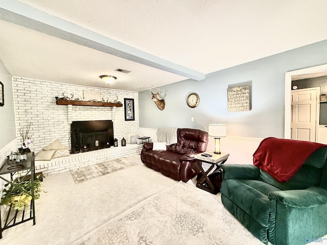 living room with a wainscoted wall, visible vents, a textured ceiling, and beam ceiling